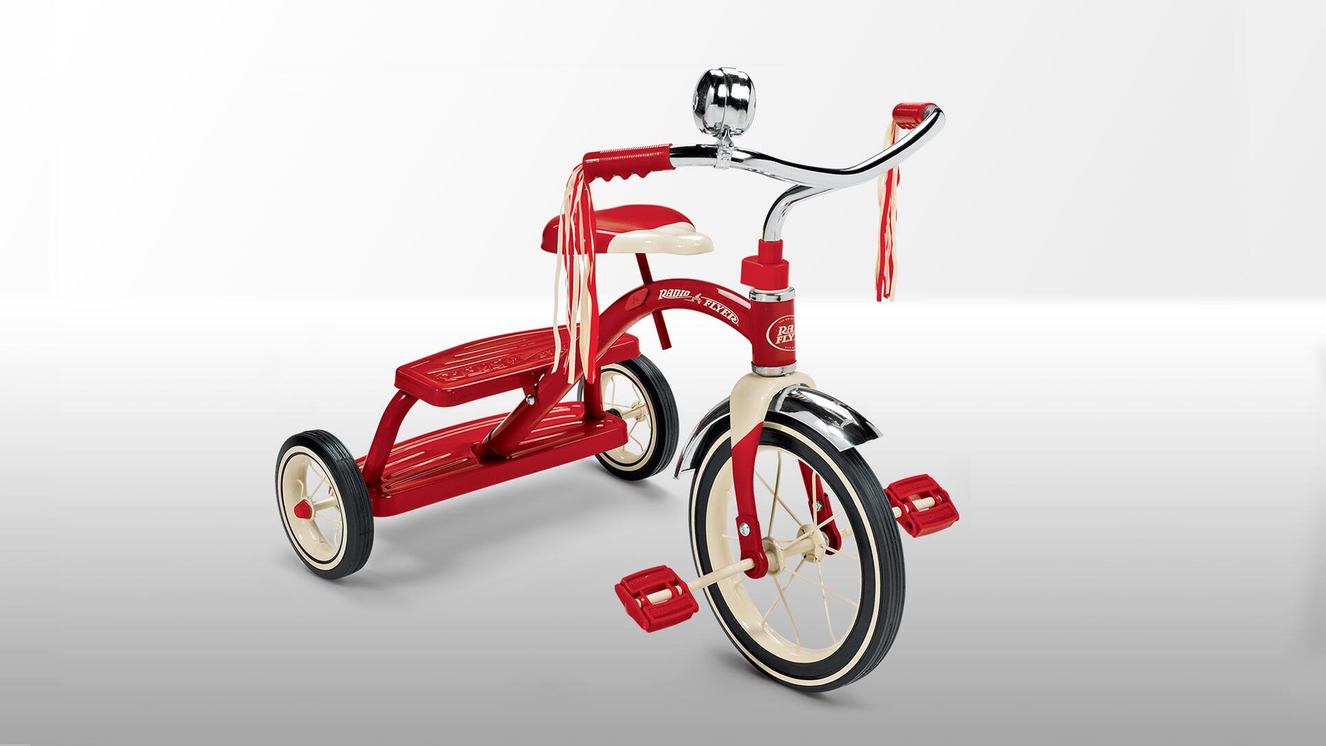 Red tricycle with chrome handlebars and streamers, large front wheel, and beige accents on a white background.