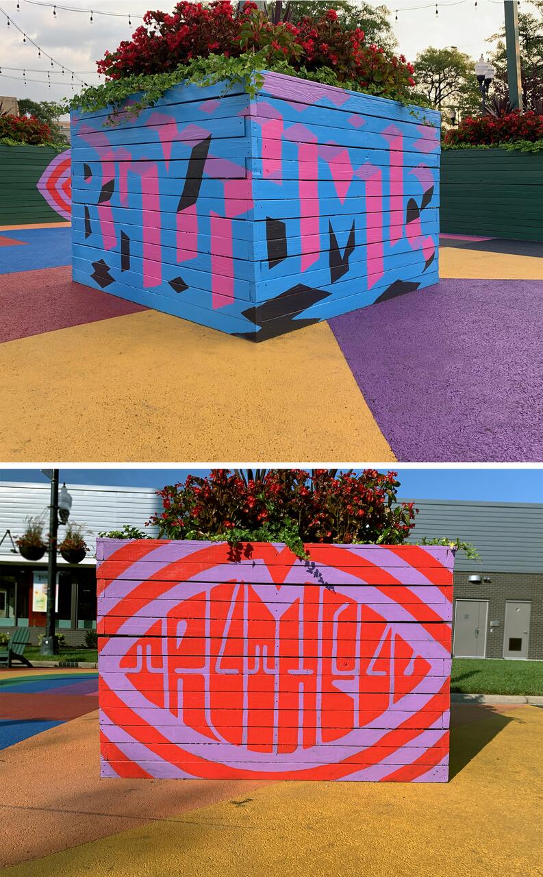 A large, square planter with colorful flowers on top, featuring abstract, vibrant murals with text. The top image shows a blue planter with pink and black text, while the bottom one has a red and purple striped pattern. Both are on a colorful, geometric ground.